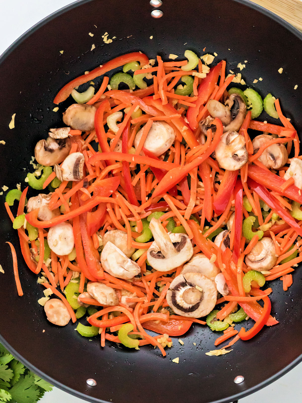 Mushrooms, carrots, and celery in a wok.