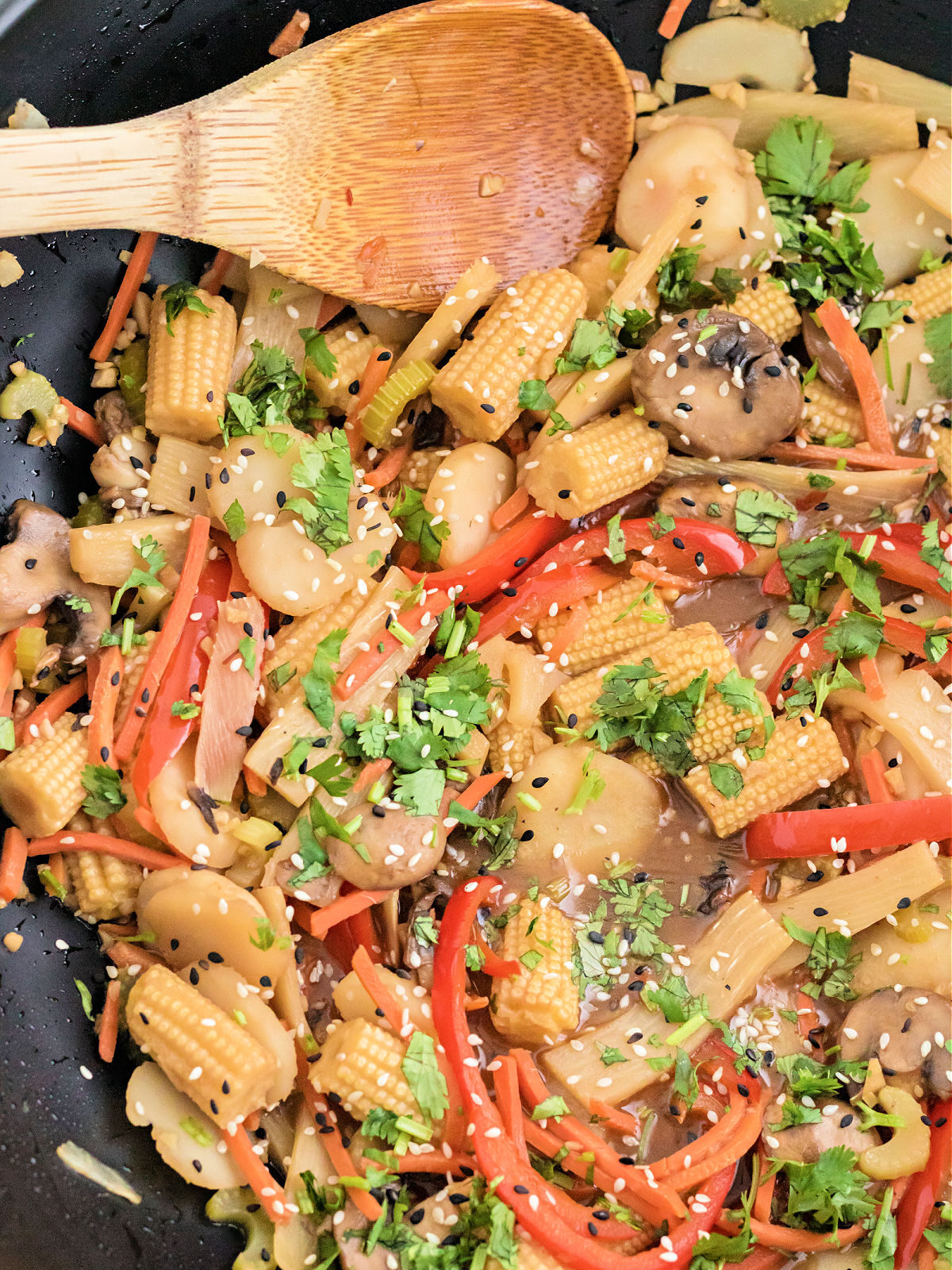 Stir frying vegetables in a wok with a wooden spoon.