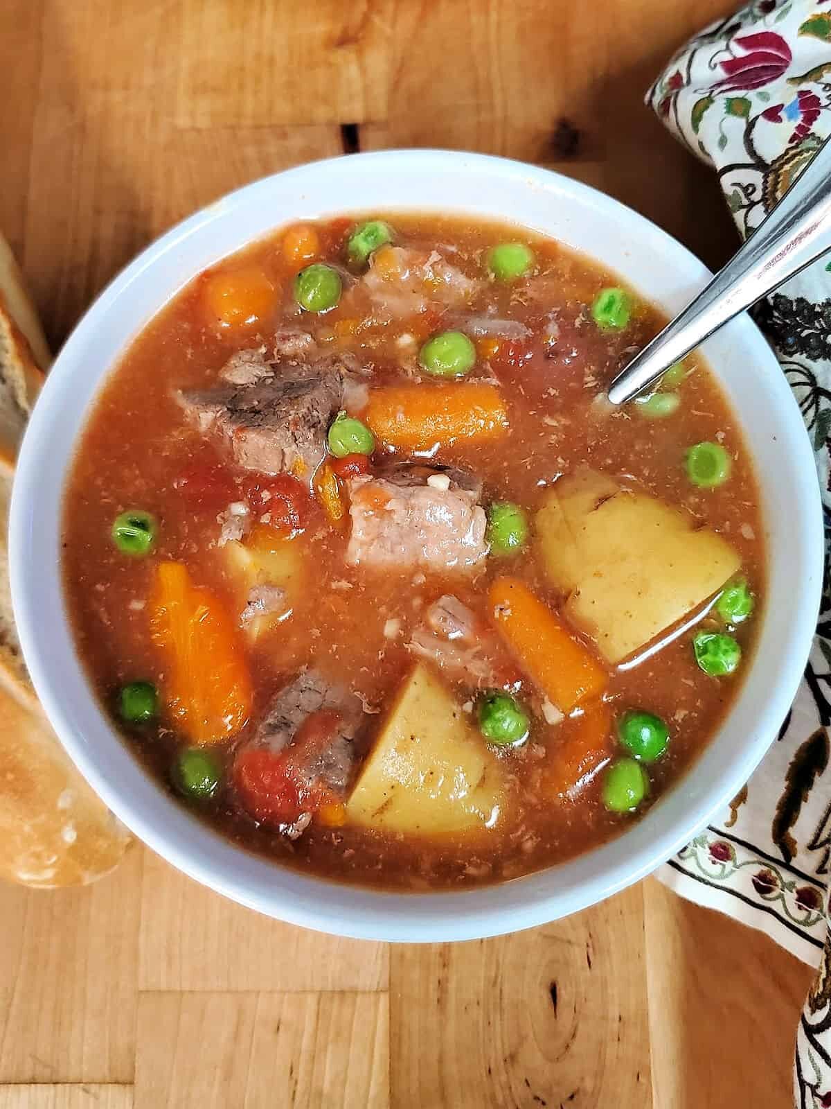 Bowl of hearty beef stew and slice of bread.