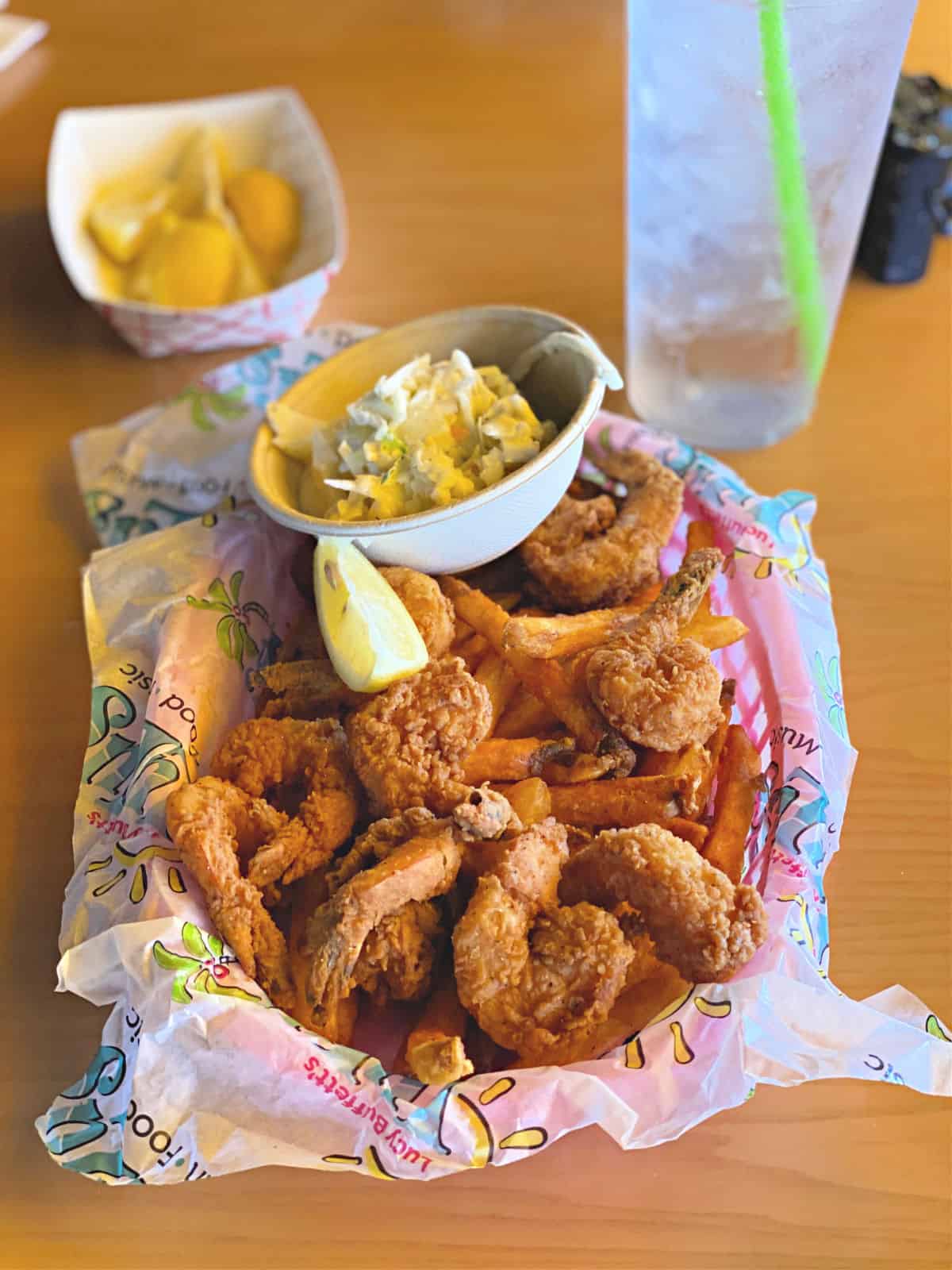 Shrimp basket with French fries and coleslaw with lemon wedges.
