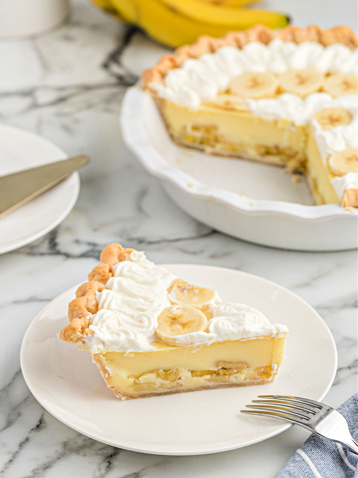 Slice of banana pie on a plate with a fork.