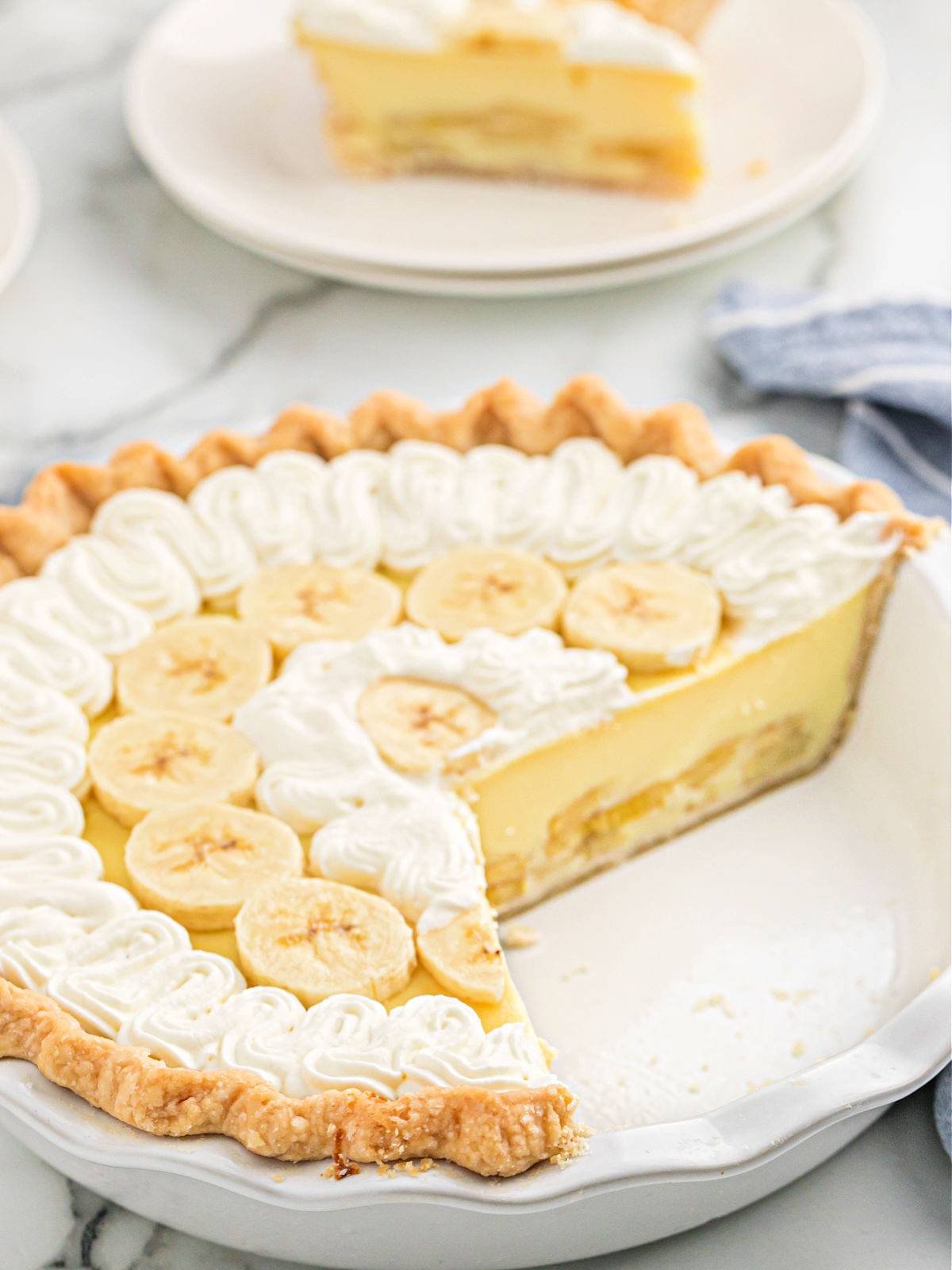Banana cream pie in a white ceramic pie plate.