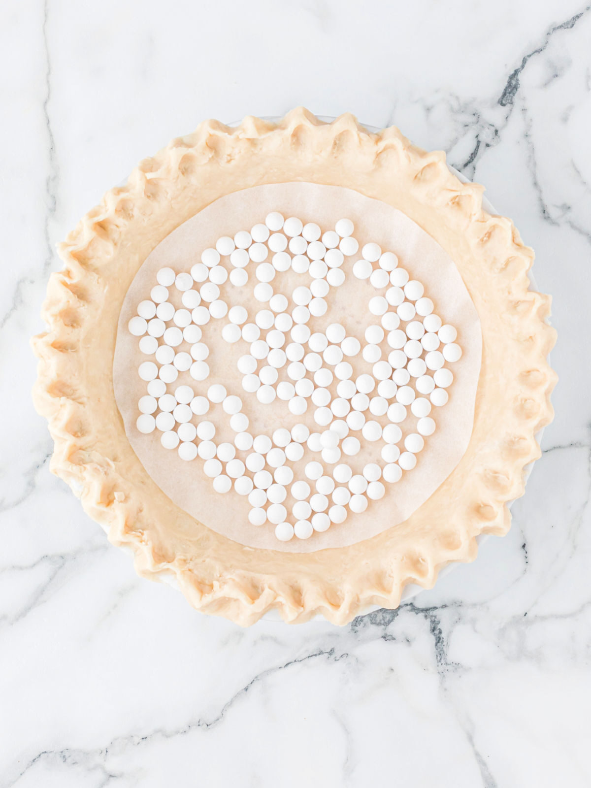 Homemade pie crust with pie weights on top before baking.