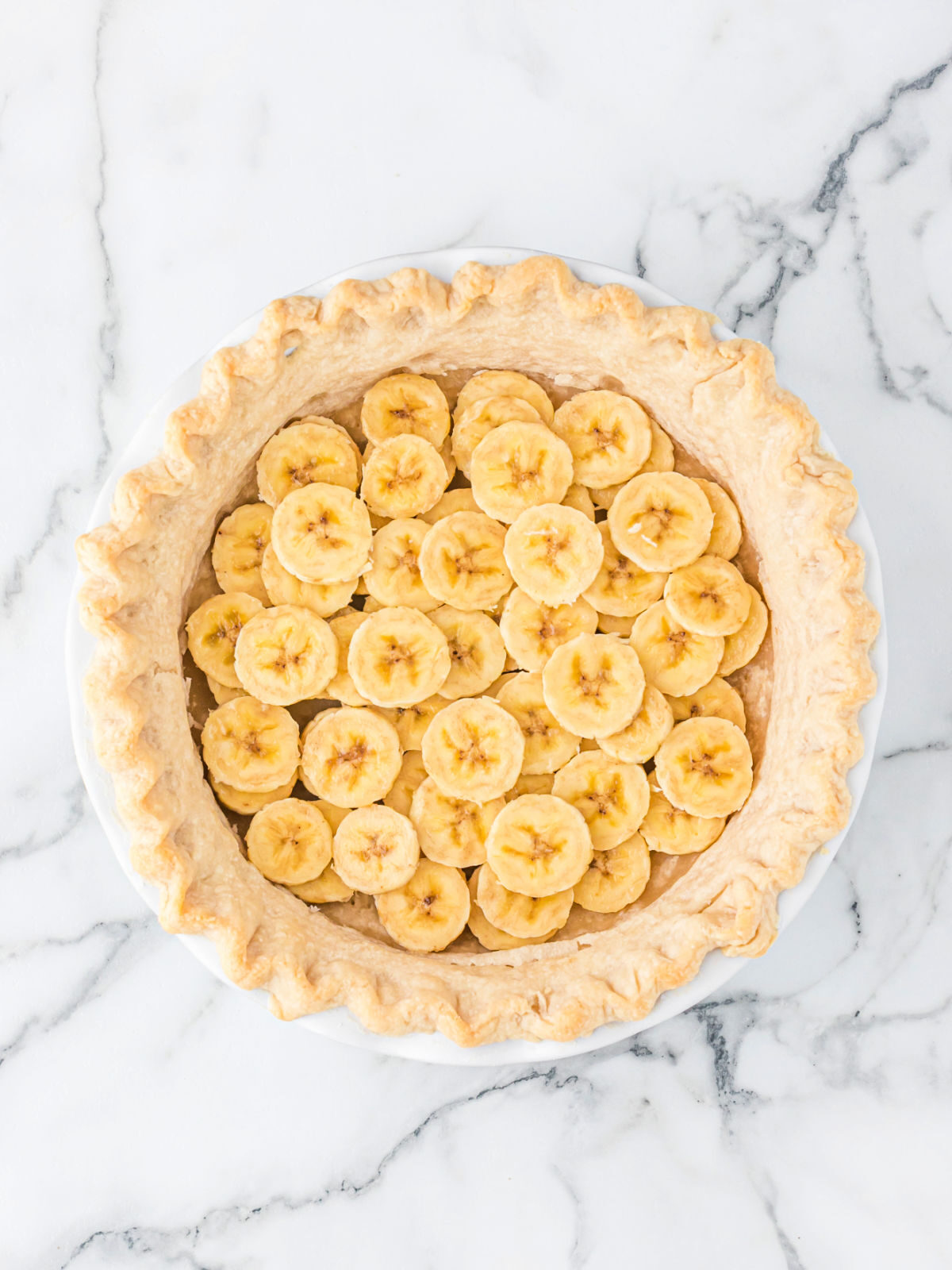 Layer of sliced bananas in the bottom of a pie crust.