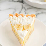Slice of banana cream pie topped with whipped cream and bananas.