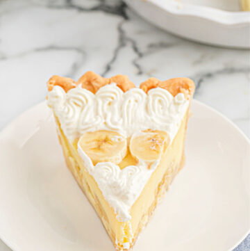 Slice of banana cream pie topped with whipped cream and bananas.