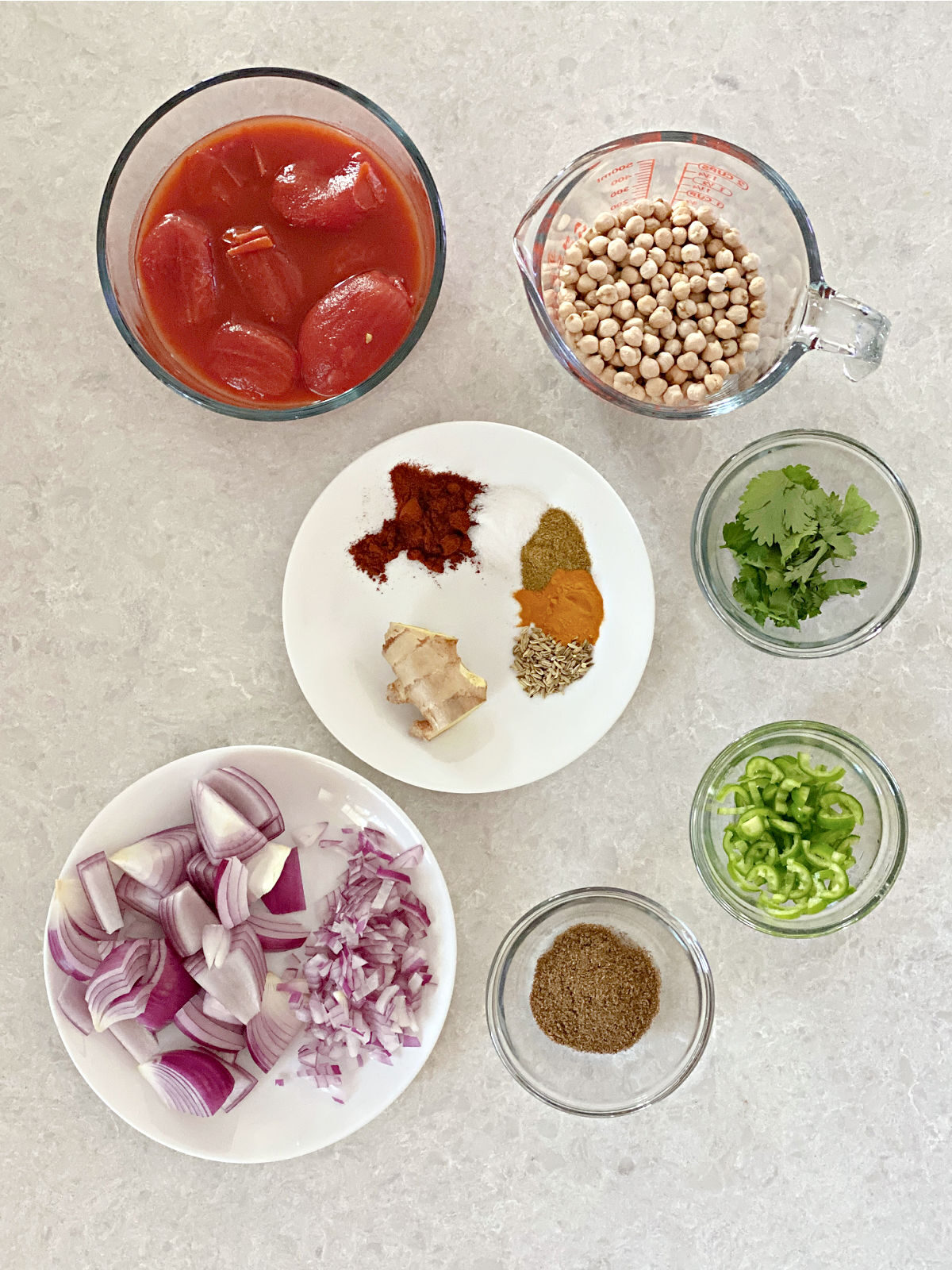 Tomatoes, chickpeas, spices, onions, cilantro, serrano, and garam masala in bowls.