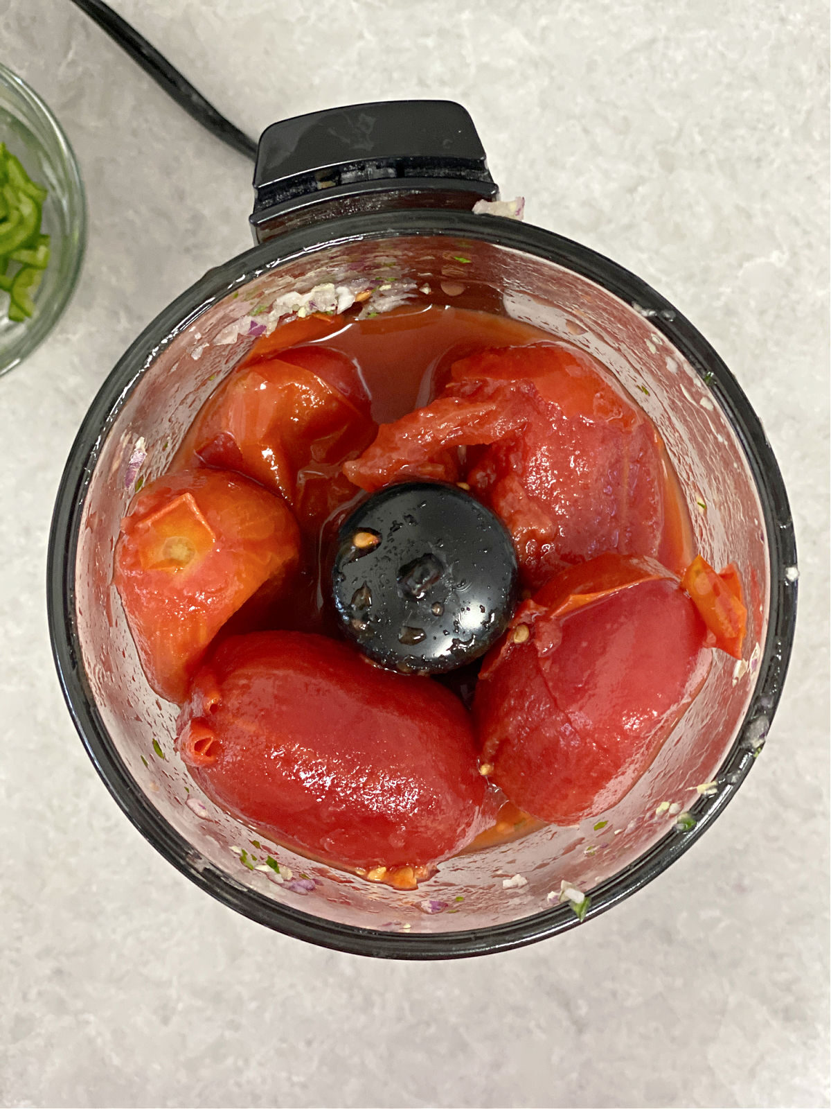 Whole tomatoes in a food processor.