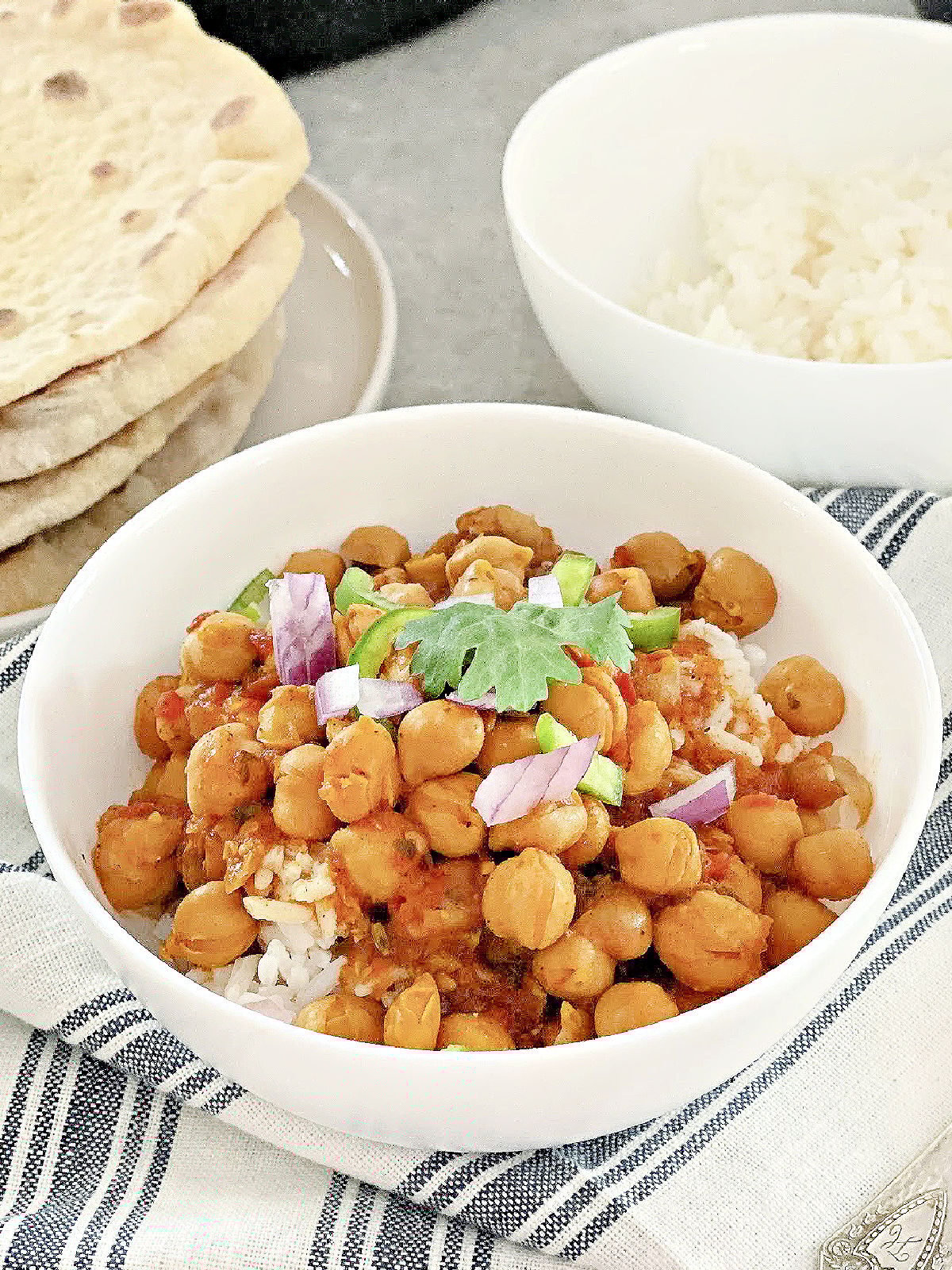 Bowl of chana masala, bowl of rice, and stack of naan.
