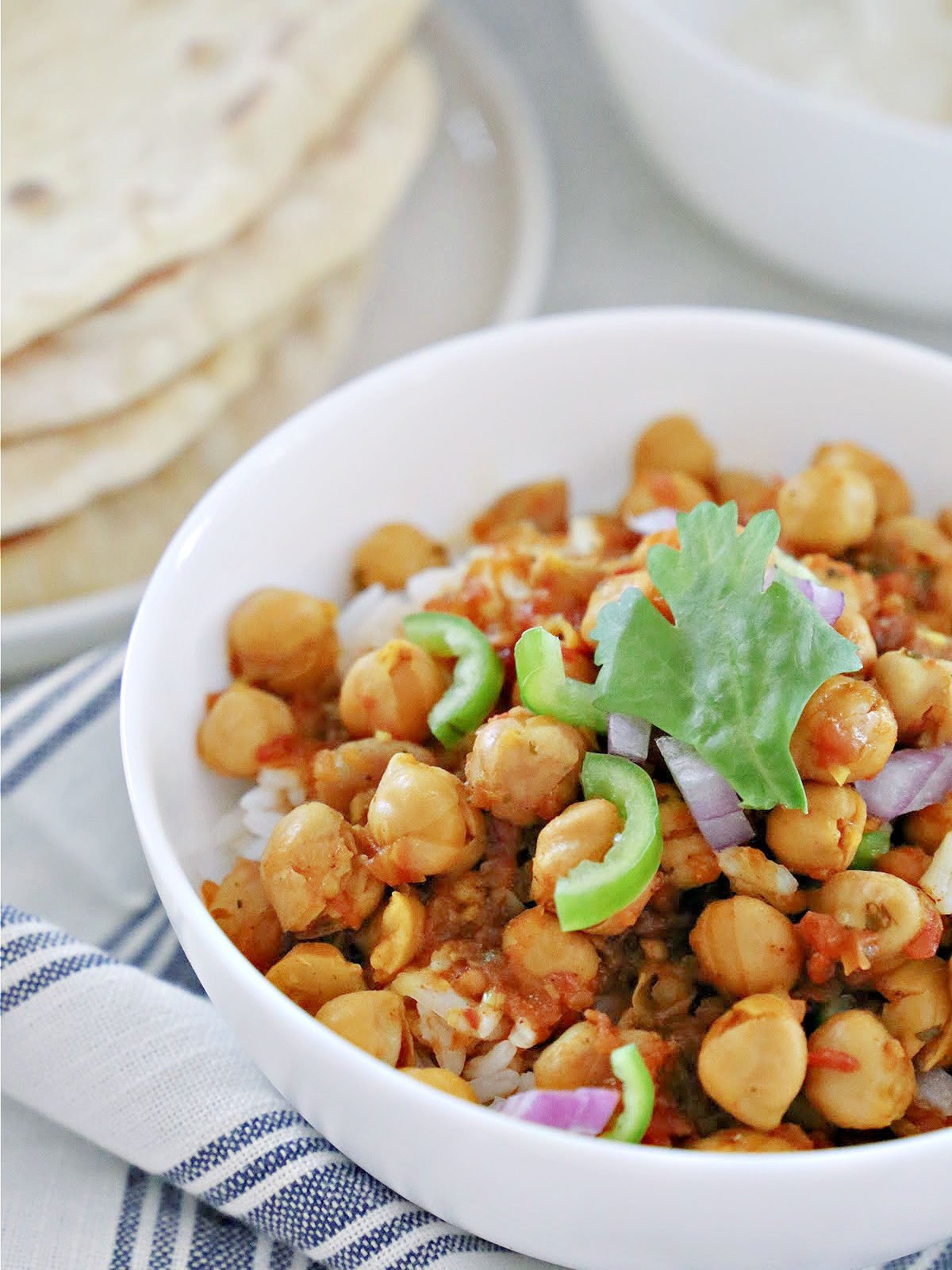Bowl of rice and chana masala with stack of naan.