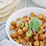 Bowl of rice and chana masala with stack of naan.