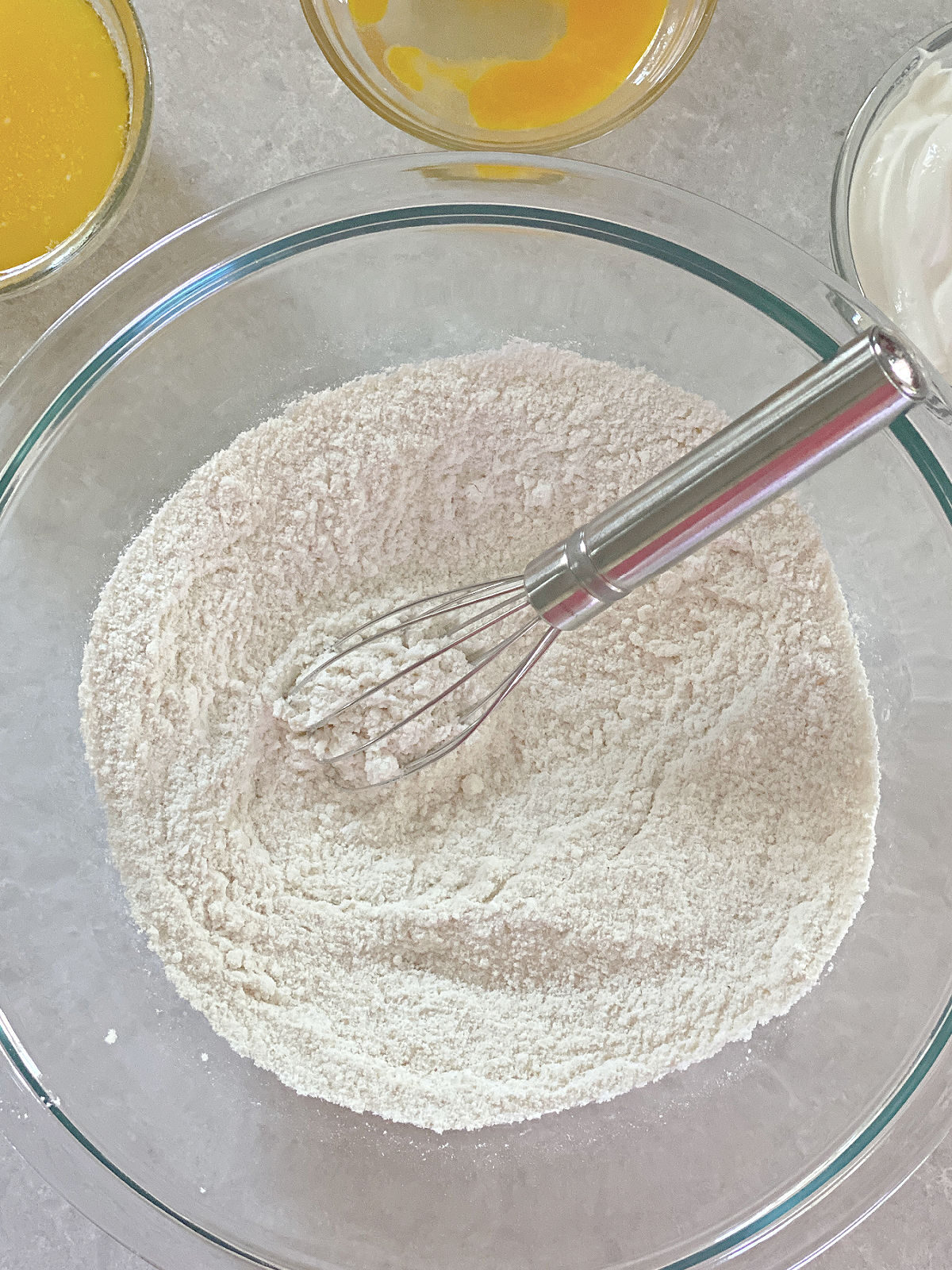 Flour, sugar, and cornmeal in a bowl with a whisk.