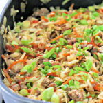 Cabbage, sausage, and scallions in a skillet.