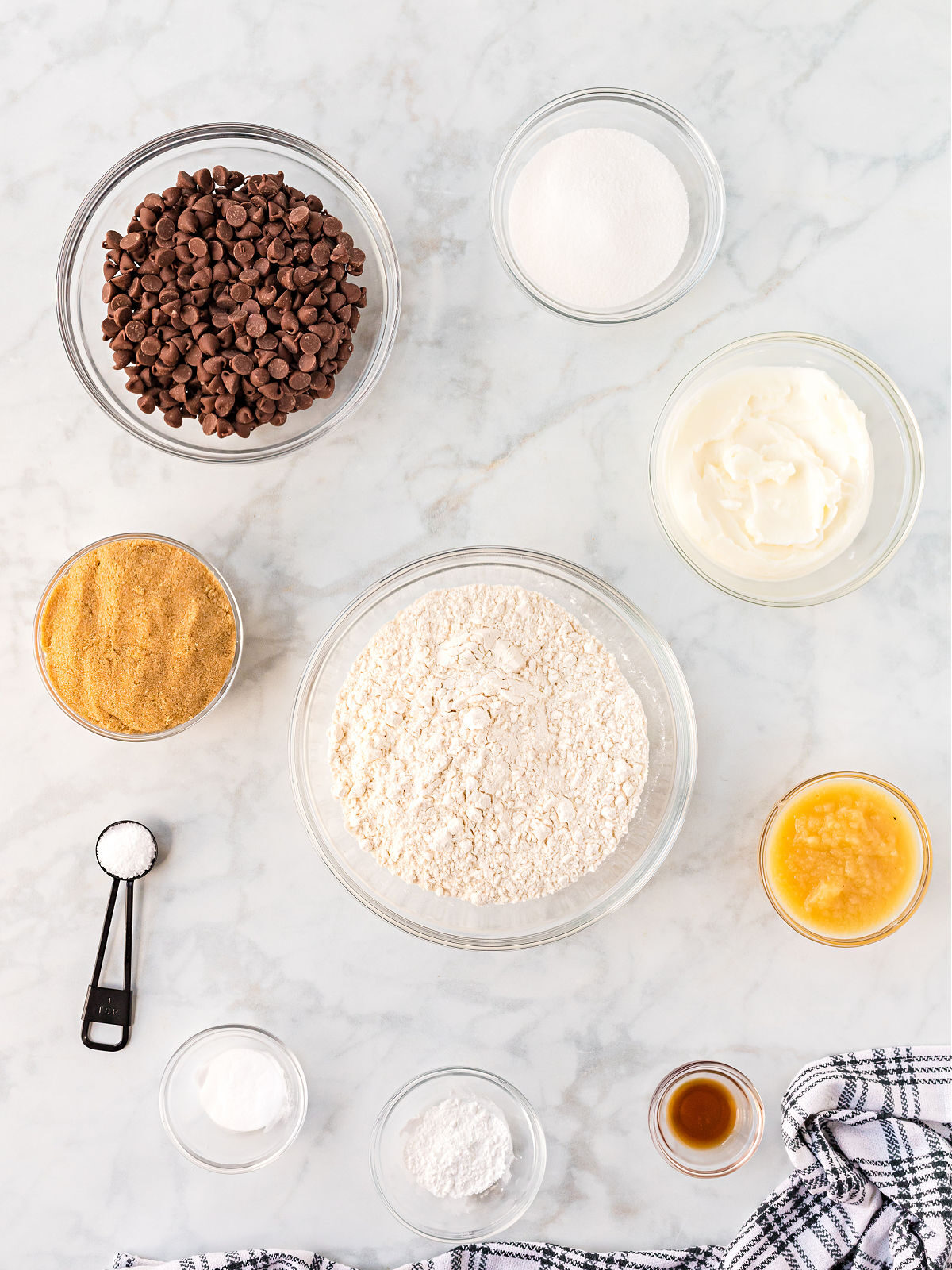 Bowls of flour, chocolate chips, sugar, brown sugar, shortening, apple sauce, and vanilla.