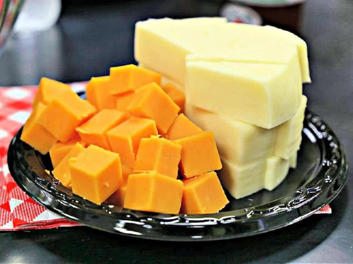 Cheddar and white cheese on a black plate.