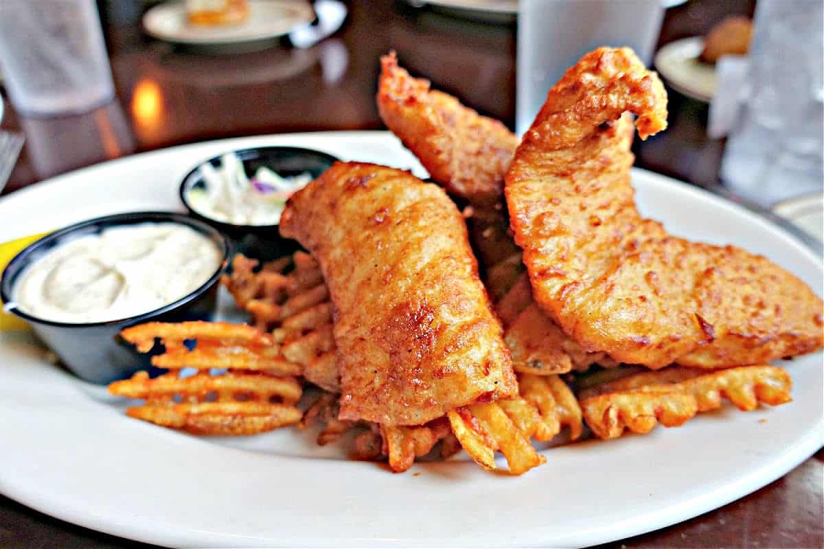 Fish and Chips at Beefeaters British Grille & Ale House White plate topped with waffle fries and fried fish.