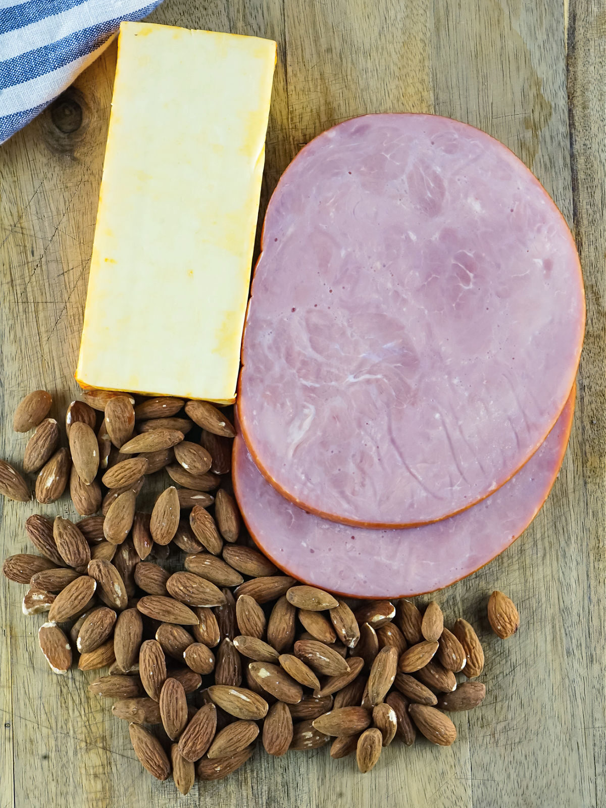 Ham, cheese, and almonds on a cutting board.