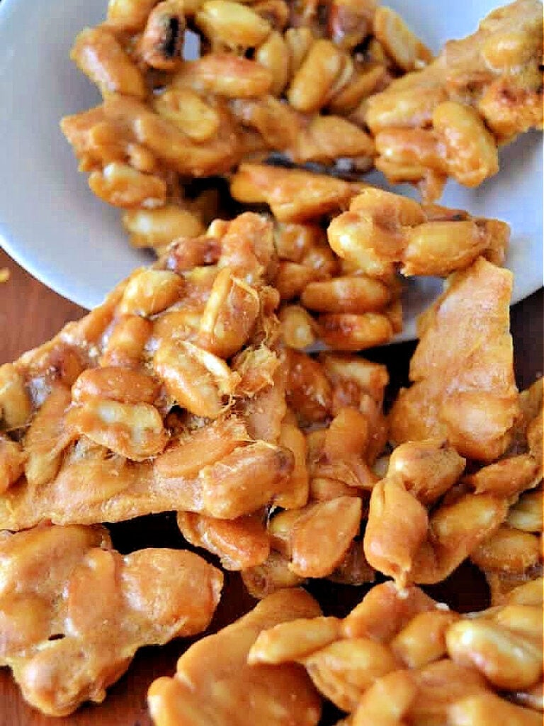 Peanut brittle spilling out of a bowl onto a counter top.