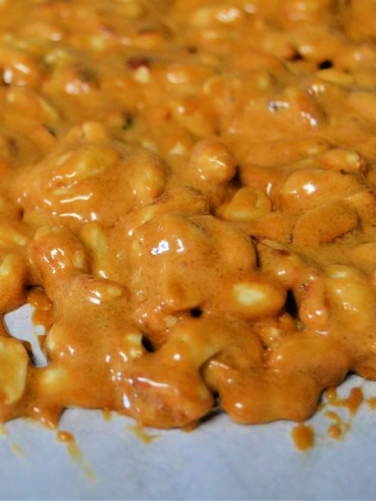 Close up view of hot peanut brittle on parchment paper.