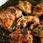 Chicken thighs cooked in a balsamic reduction in a skillet.