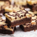 Slices of cheesecake brownies with chocolate chips stacked on each other.