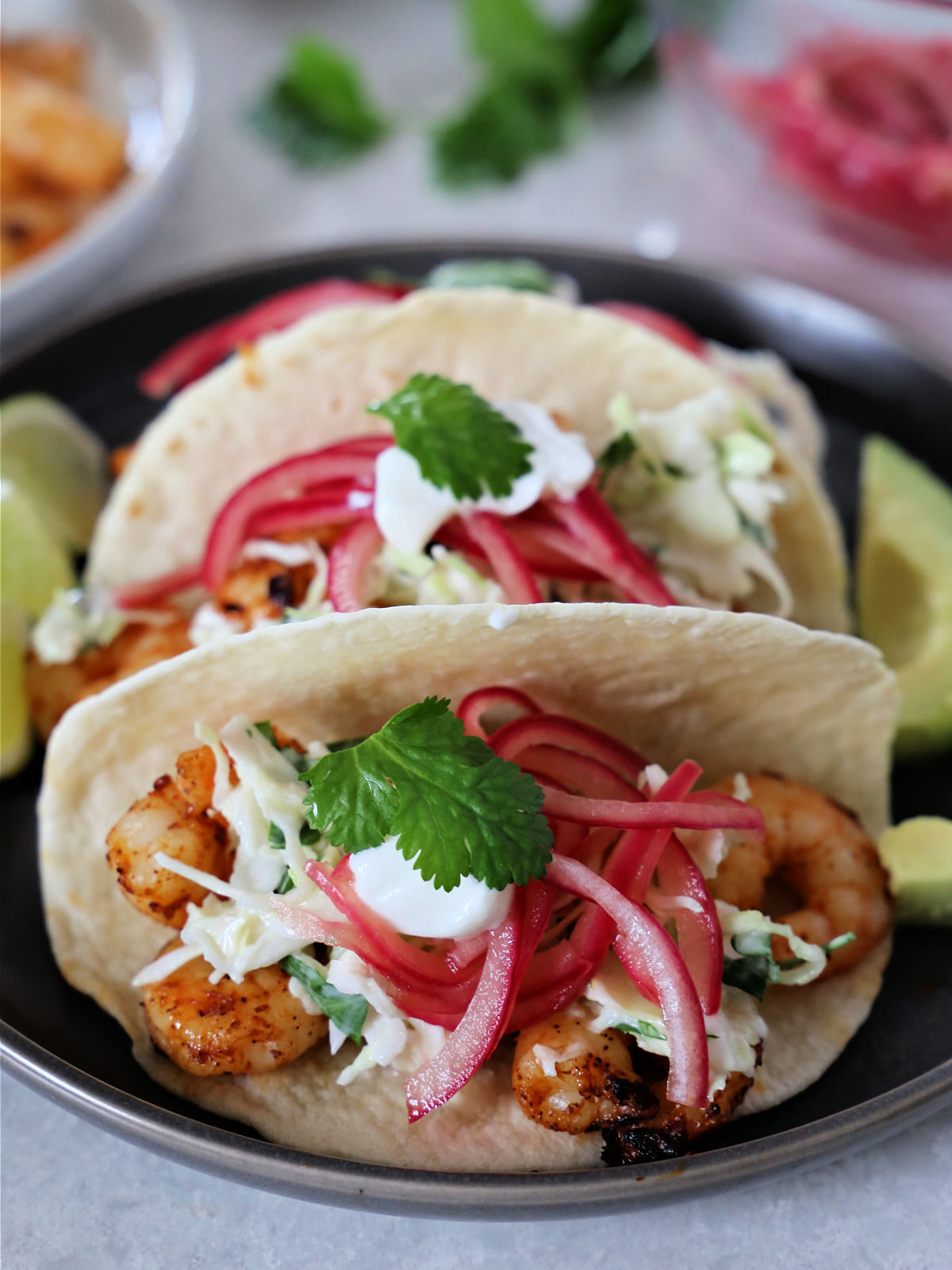 Three grilled shrimp tacos on a brown plate.