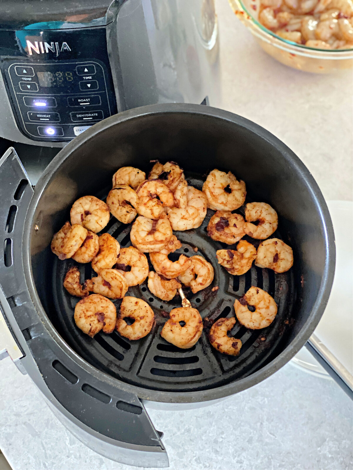 Air fried shrimp in an air fryer basket.