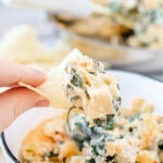 Scoop of spinach dip on a tortilla chip.