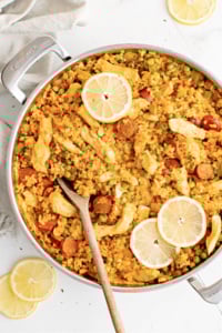 Cooked chicken paella with chorizo and topped with lemon slices.