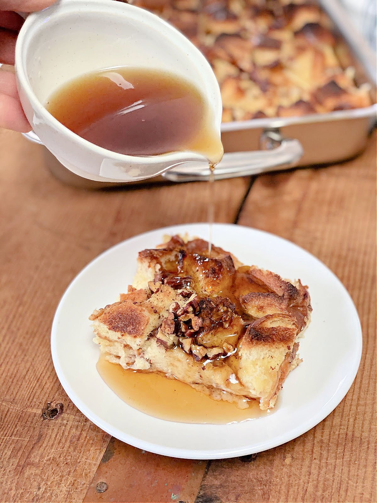 Maple syrup being poured onto a slice of French toast casserole.
