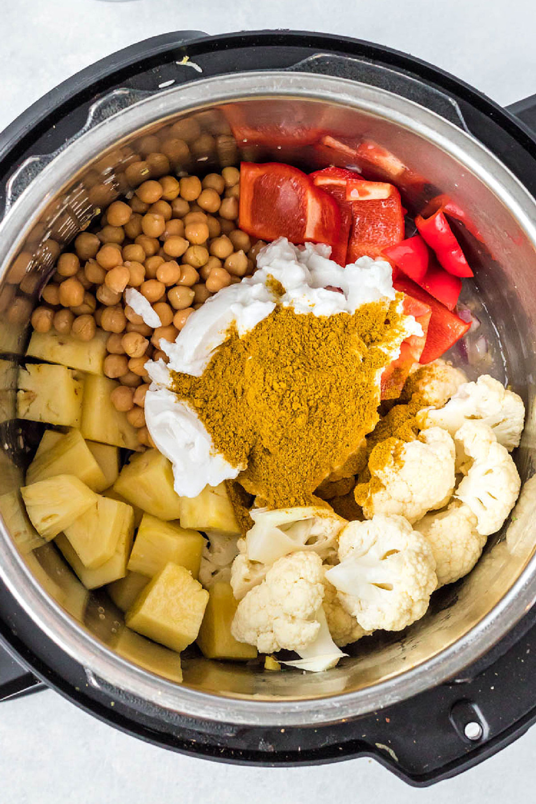 Cauliflower, pineapple, chickpeas, bell peppers, coconut milk, and curry in an Instant Pot.