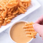 Person dipping a crinkle cut French fry into homemade Chick-Fil-A sauce.