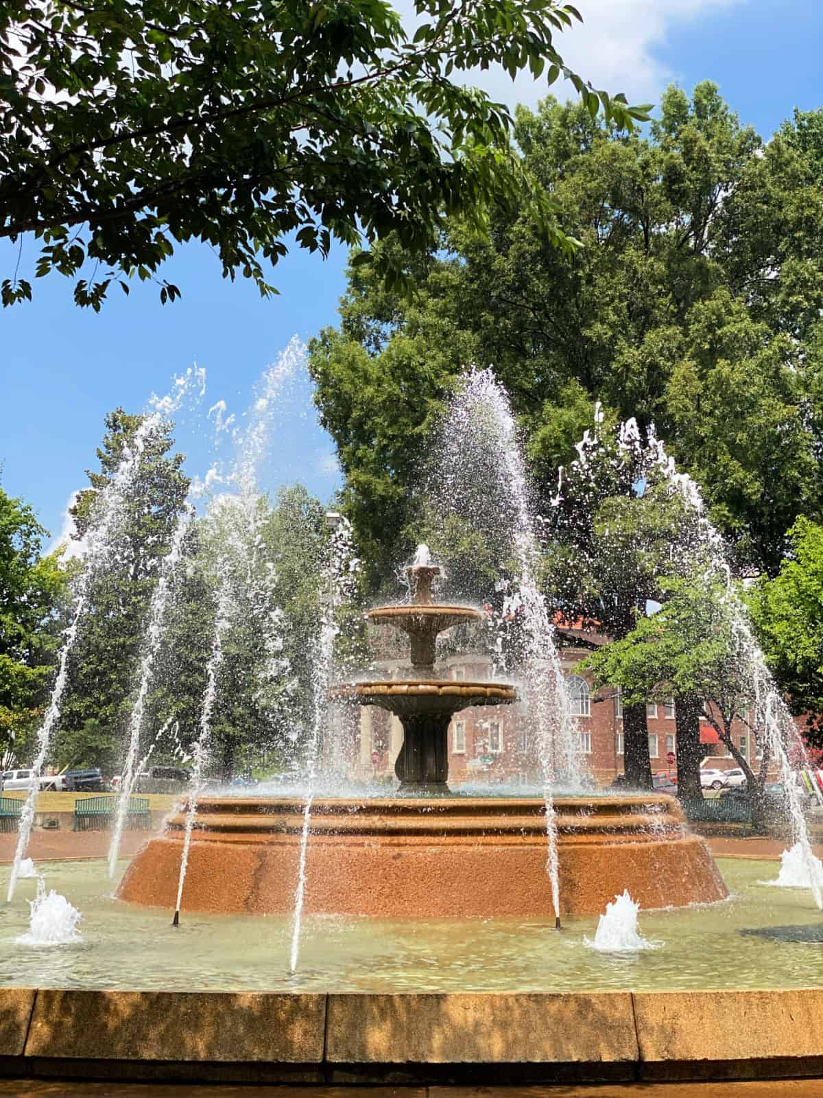 Water fountain in front of green trees.