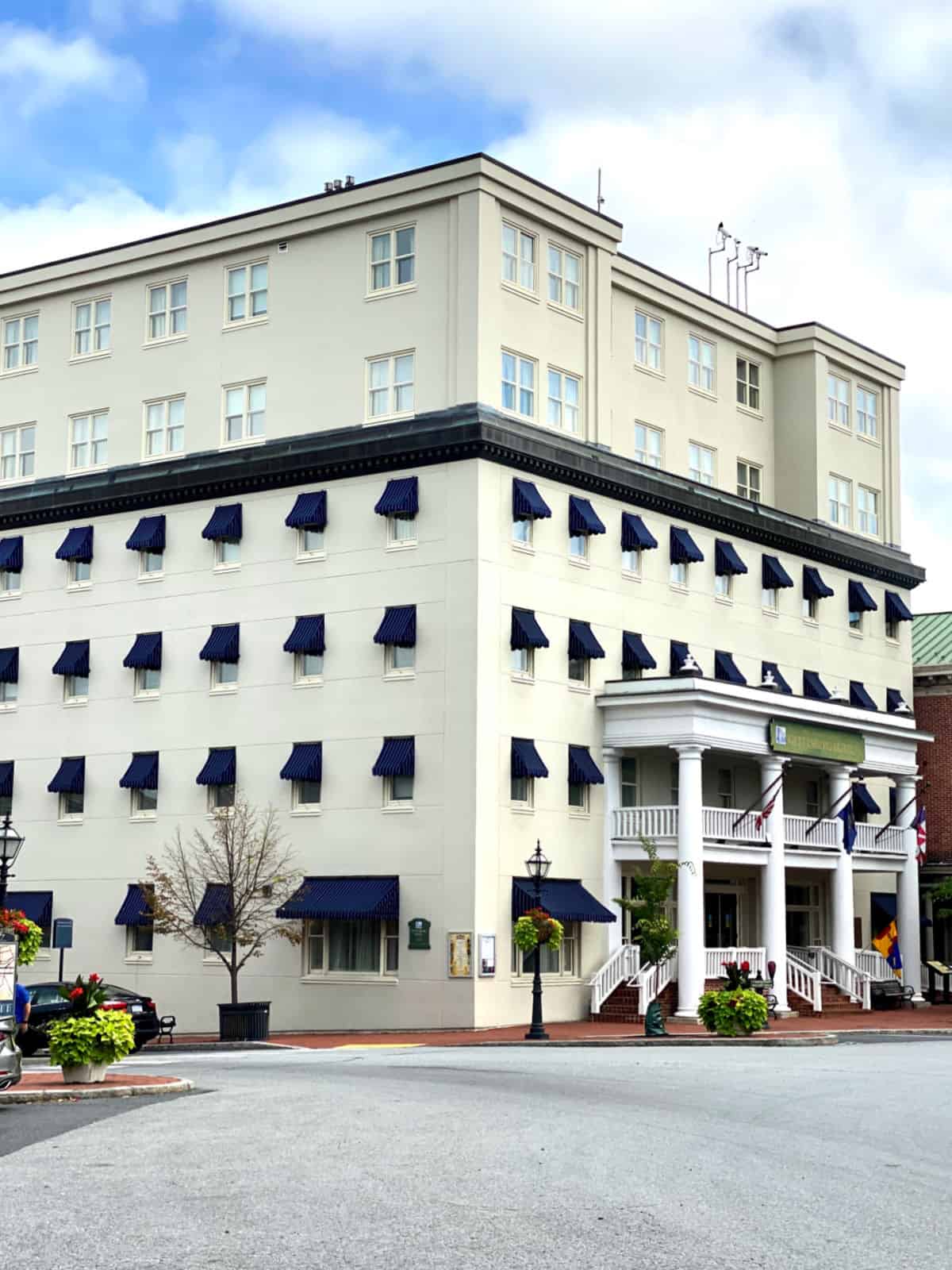 White hotel with blue awnings over windows.