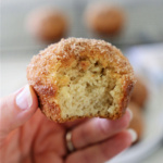 Hand holding a muffin that has had a bite taken out of it.