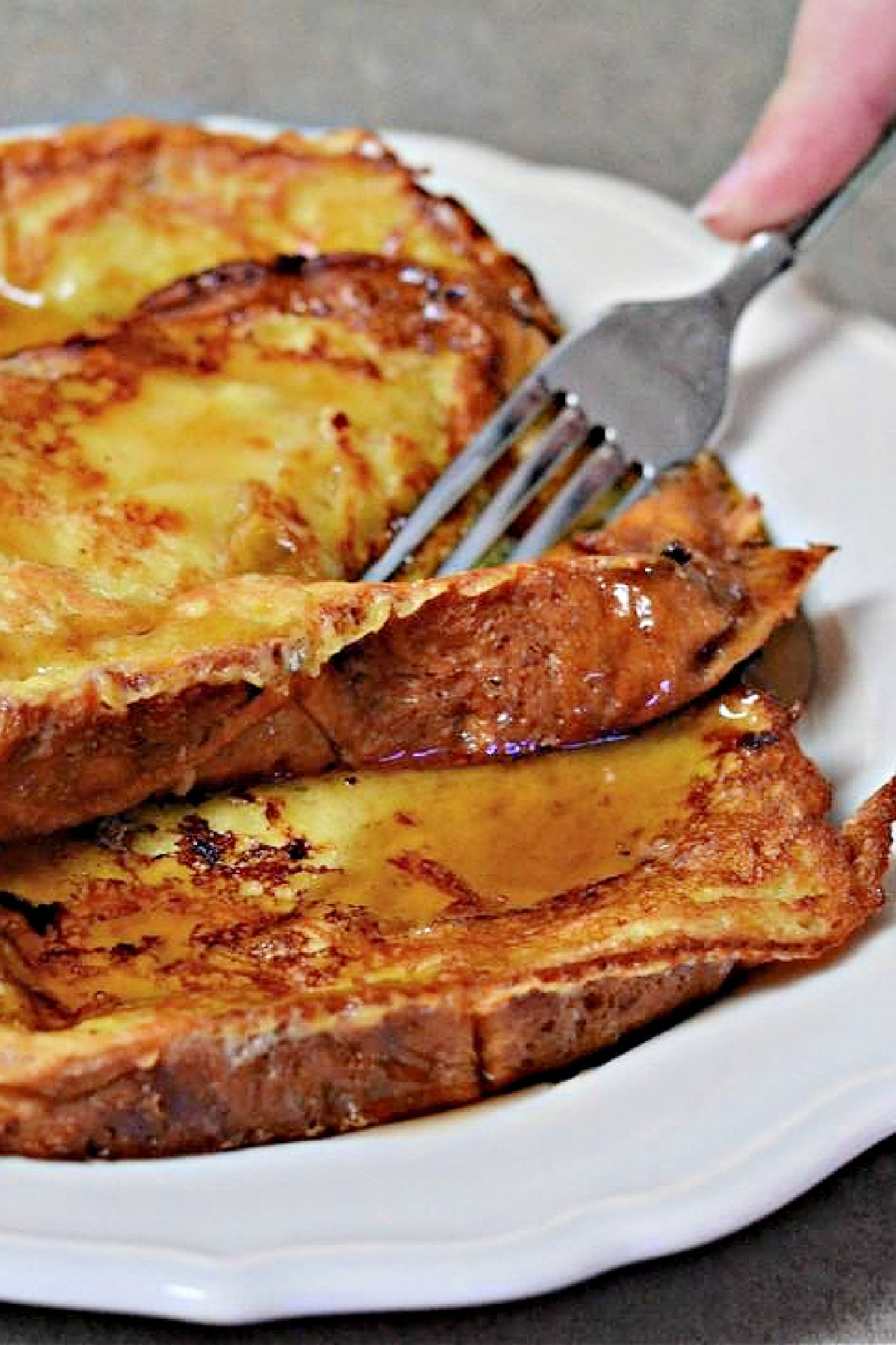 How to Make Brioche French Toast Fork cutting into stack of French toast.
