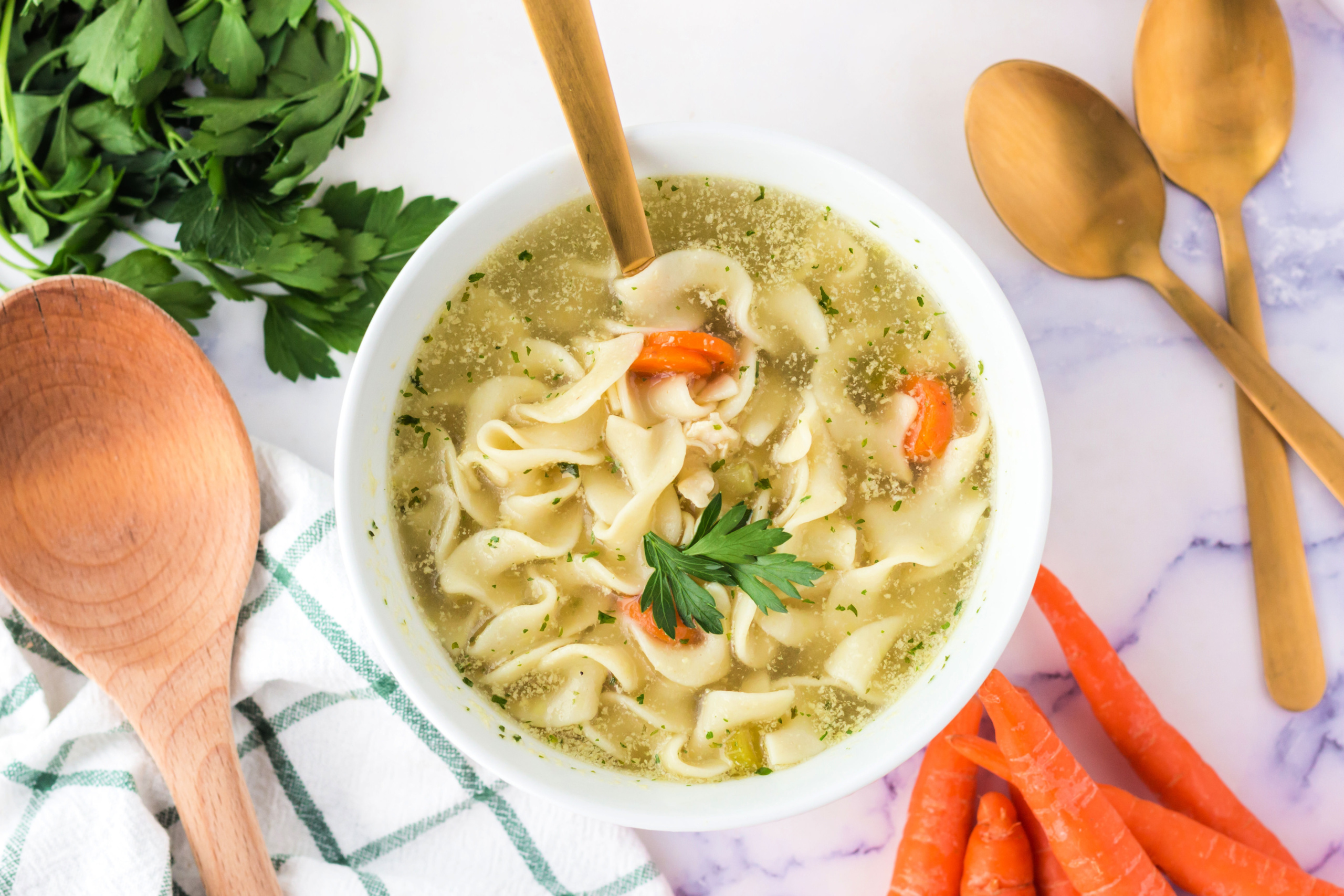 Bowl of chicken noodle soup garnished with parsley.