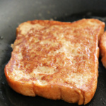 Piece of French toast cooking in a nonstick skillet.