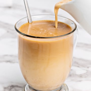 Pumpkin spice creamer being poured into a cup of coffee.