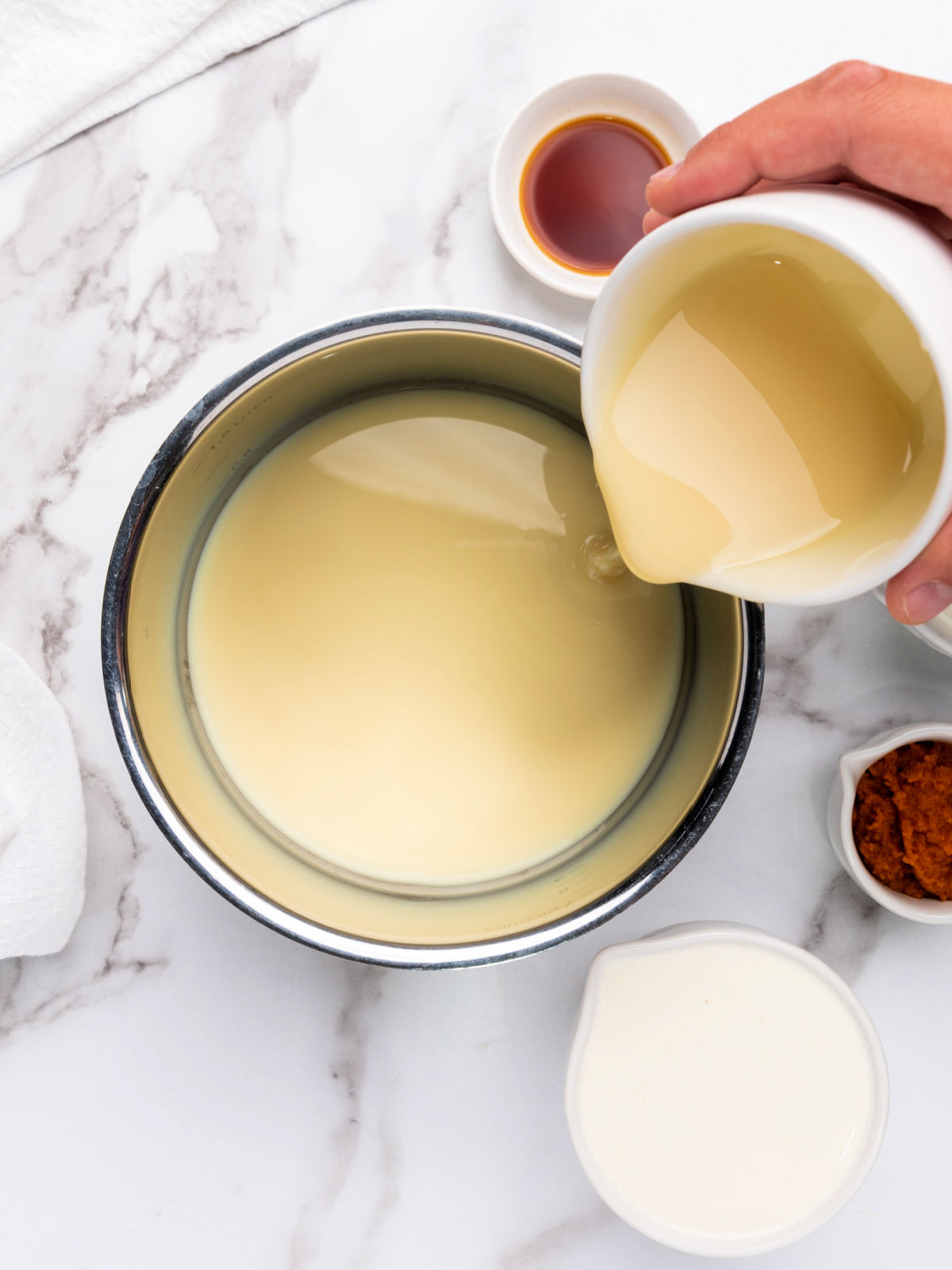 Pouring condensed milk into a small pot.
