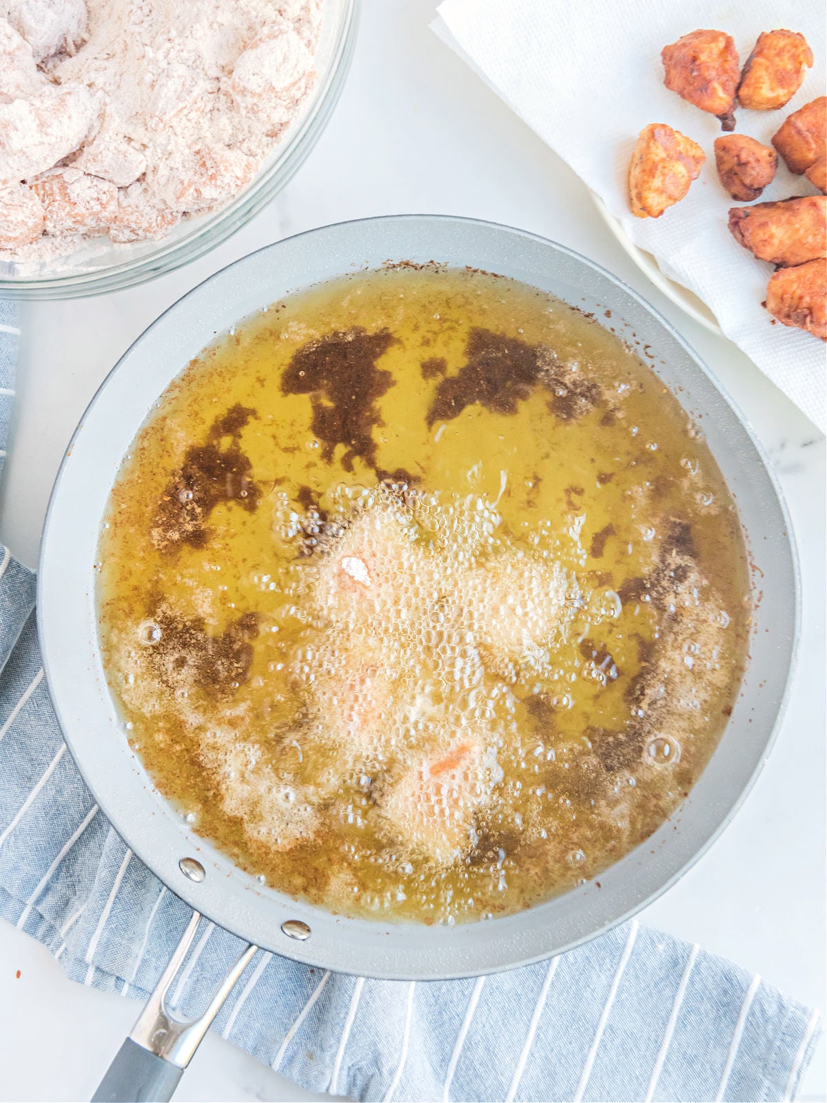 Chicken nuggets frying in a pan.