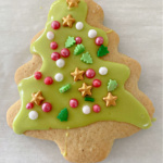 Christmas tree cookie decorated with green icing and sprinkles.