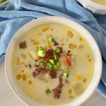 Bowl of corn chowder topped with bacon and green onions.