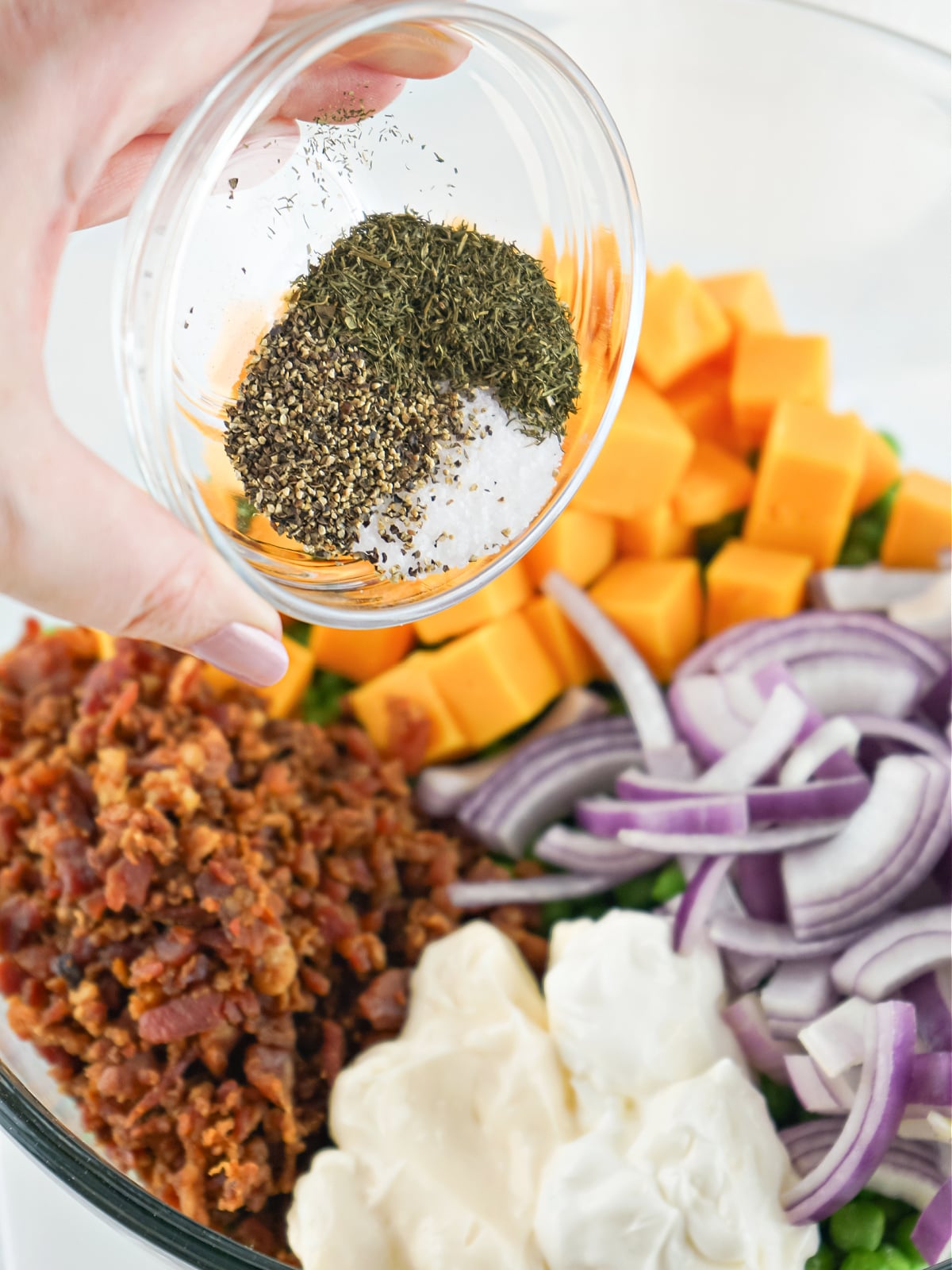 Adding seasoning to pea salad ingredients.