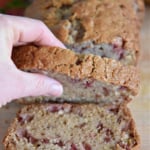 Woman's hand getting a slice of strawberry bread.