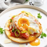 Plate of huevos rancheros on top of a tortilla.