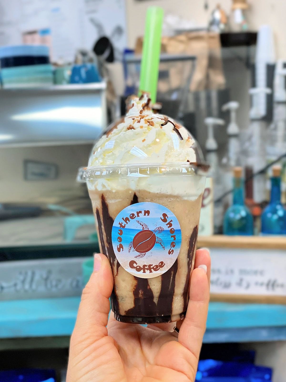 Woman holding a bushwacker frappe topped with whipped cream.