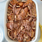 Croissant bread pudding baked in a white casserole dish topped with melted Nutella.