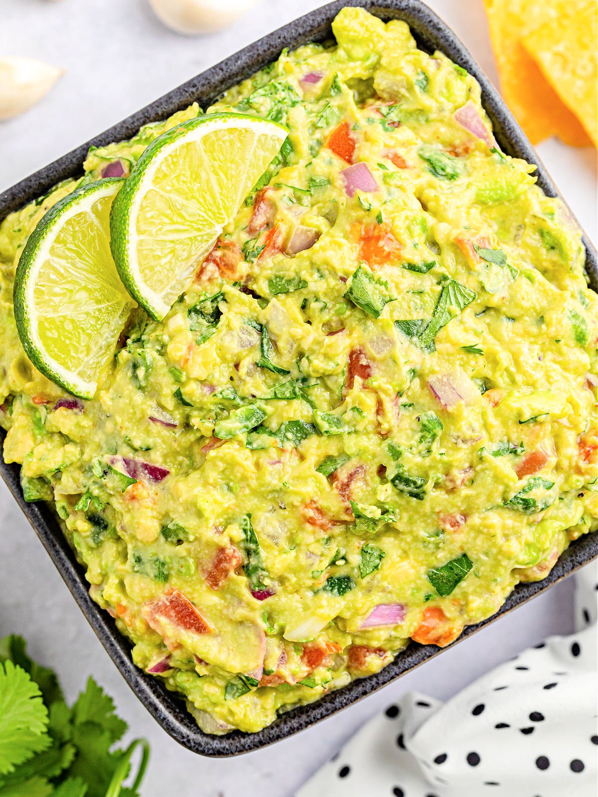 Bowl of guacamole topped with lime slices.