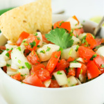 Tortilla chip in a bowl of pico de gallo.